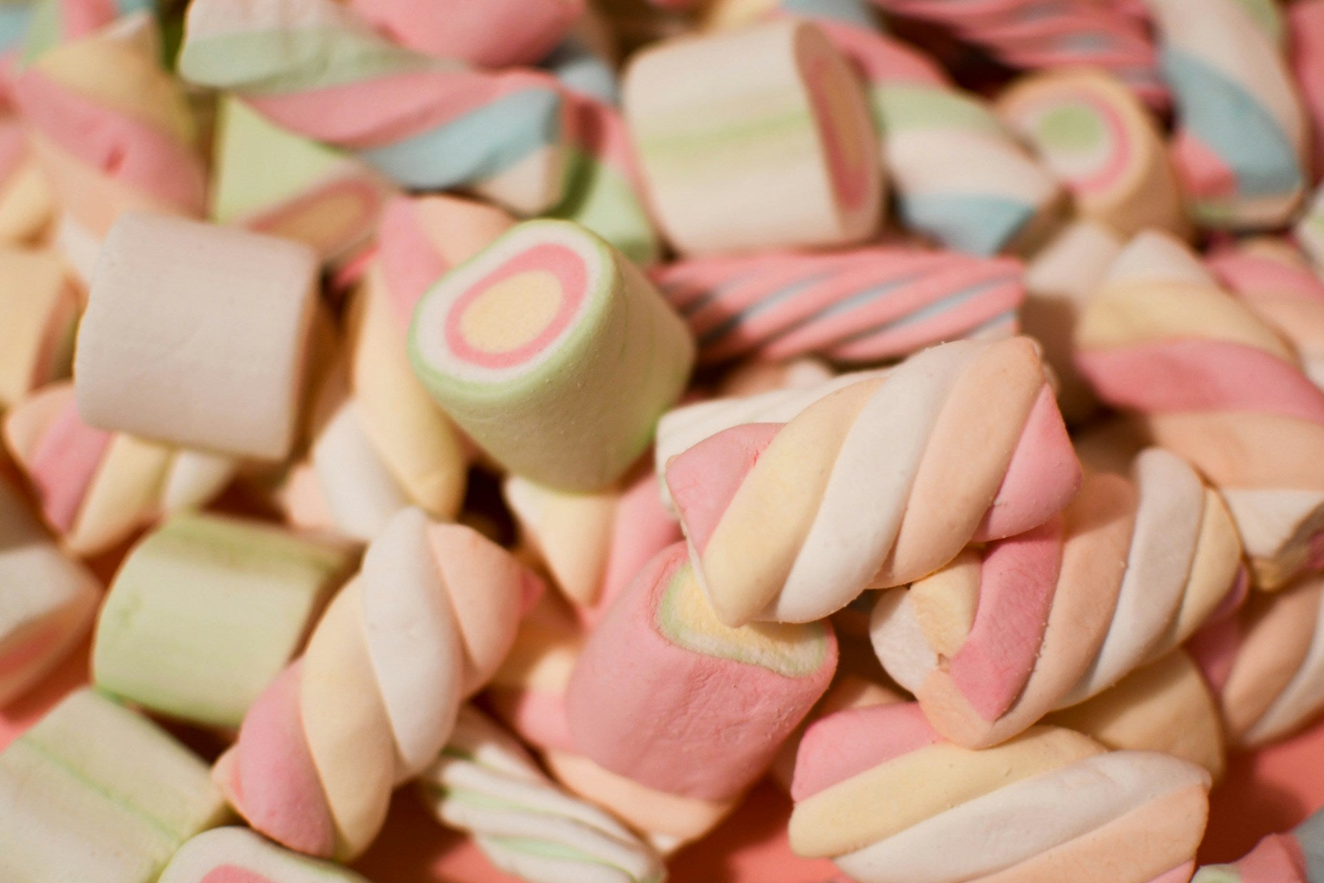 Mélange de guimauves torsadées pastel et de bonbons moelleux aux couleurs douces.